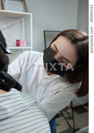 piercings on an ear. Conch and helix piercings close up. Professional holding the jewel. 90006581