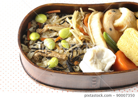 A bird's-eye view of the Makunouchi lunch box containing a lot of side dishes such as hijiki and edamame rice, shumai, omelet, and simmered dishes. A bird's-eye view of the Makunouchi lunch box containing a lot of side dishes such as hijiki and edamame rice, shumai, omelet, and simmered dishes. 90007350
