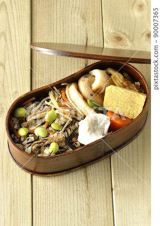 Makunouchi午餐盒的鳥瞰圖，裡面有很多小菜，如羊栖菜和毛豆飯、燒麥、煎蛋捲和燉菜。 90007365