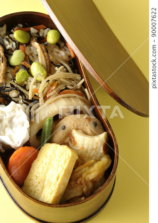 Makunouchi午餐盒的鳥瞰圖,裡面有很多小菜,如羊栖菜和毛豆飯、燒麥、煎蛋捲和燉菜。 Makunouchi午餐盒的鳥瞰圖,裡面有很多小菜,如羊栖菜和毛豆飯、燒麥、煎蛋捲和燉菜。 90007622