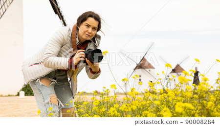 Tourist with camera in front of the windmills of the Mota del cuervo. Spain Tourist with camera in front of the windmills of the Mota del cuervo. Spain 90008284