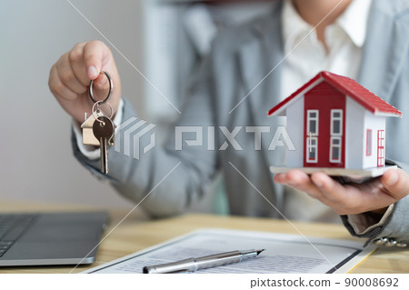 Insurance concept the real estate representative holding a house key on the right hand and the house model on the left hand Insurance concept the real estate representative holding a house key on the right hand and the house model on the left hand 90008692