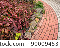 Cobblestone stone sidewalk with flower bed. Landscaping of town, ensuring safety of pedestrians. Accessible environment and environmental friendliness of city. Old cobblestones form atmosphere of 90009453