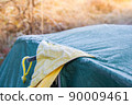 Roof of tourist tent under the morning sun. Green waterproof fabric was covered with cold and condensation from frost. Equipment for survival in wild 90009461