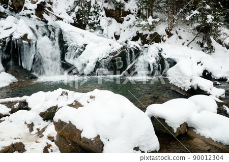 A small active waterfall. Clean mountain stream, snowy winter landscape, wildlife background 90012304