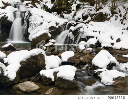 A small active waterfall. Clean mountain stream, snowy winter landscape, wildlife background 90012518