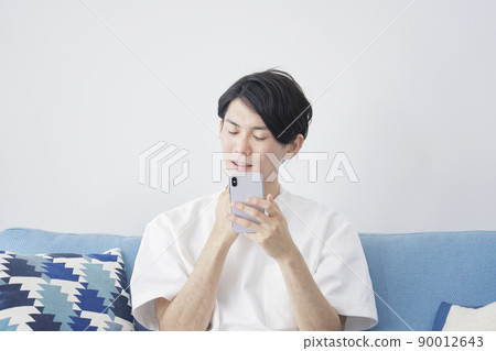 A man who thinks with a smartphone in the living room A man who thinks with a smartphone in the living room 90012643