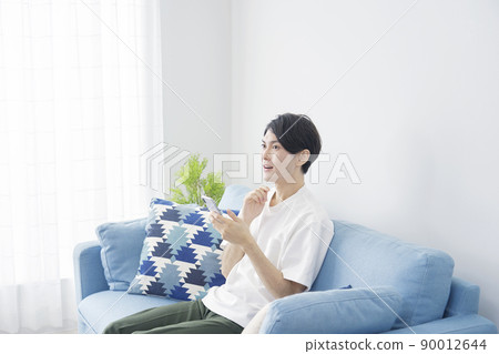 A man who imagines holding a smartphone in the living room 90012644