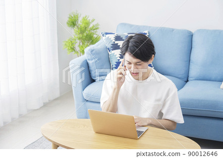 A man calling on his smartphone in the living room A man calling on his smartphone in the living room 90012646