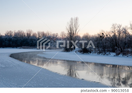 Photo the snow-covered river did not freeze in winter.The river flows in winter. Snow on the branches of trees. Reflection of snow in the river. Huge snowdrifts lie on the Bank of the stream. Photo the snow-covered river did not freeze in winter.The river flows in winter. Snow on the branches of trees. Reflection of snow in the river. Huge snowdrifts lie on the Bank of the stream. 90013058