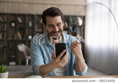 Joyful young bearded male enjoy winning message on cell screen Joyful young bearded male enjoy winning message on cell screen 90014000