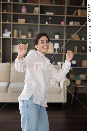 Vertical view, young woman dancing listening music through earbuds Vertical view, young woman dancing listening music through earbuds 90014127