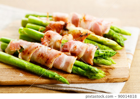 Bacon wrapped asparagus on wooden plate. Bacon wrapped asparagus on wooden plate. 90014818