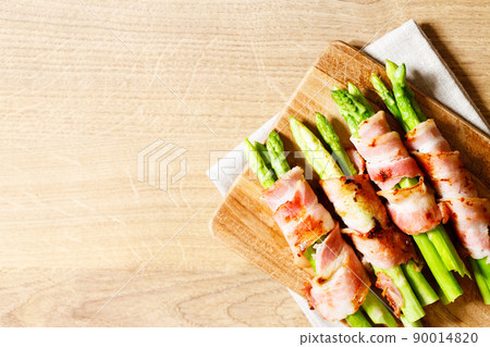 Bacon wrapped asparagus on wooden plate. Bacon wrapped asparagus on wooden plate. 90014820