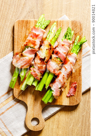 Bacon wrapped asparagus on wooden plate. Bacon wrapped asparagus on wooden plate. 90014821
