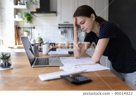 Concerned young woman thinking over domestic paperwork Concerned young woman thinking over domestic paperwork 90014922
