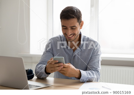 Happy young business professional man chatting on smartphone 90015169