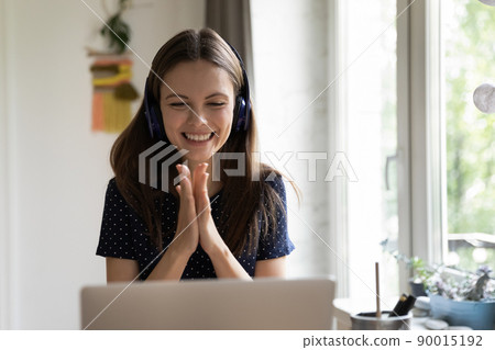 Happy cheerful laptop user girl in wireless headphones enjoying luck Happy cheerful laptop user girl in wireless headphones enjoying luck 90015192