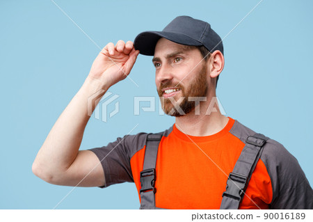 Close up of male worker in uniform holding cap and smile looking at side. Studio shoot 90016189
