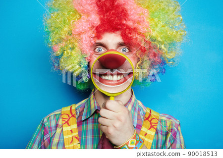 Portrait cheerful clown with the big smile on a blue background Portrait cheerful clown with the big smile on a blue background 90018513
