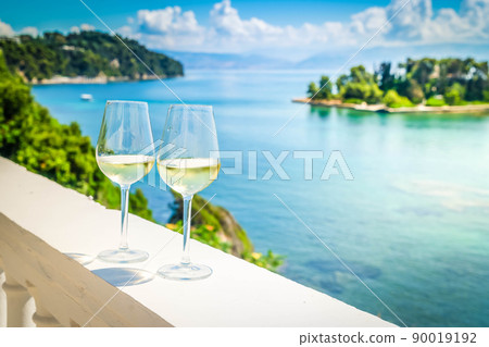 Two glasses of white wine with Corfu in background Two glasses of white wine with Corfu in background 90019192