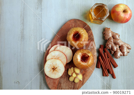 Baked apple with honey, cinnamon and ginger on a light wooden table 90019271