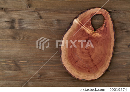 Vintage cutting board made of sawn tree on a dark wooden table 90019274
