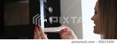 Woman in the kitchen puts a plate in the microwave 90025000