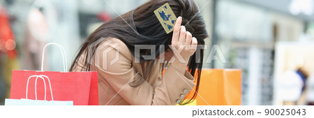 Young woman sits in a mall with a credit card in her hands Young woman sits in a mall with a credit card in her hands 90025043
