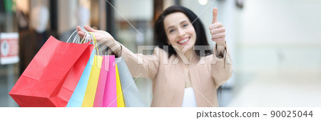 Happy woman in shopping mall with packages, close-up Happy woman in shopping mall with packages, close-up 90025044