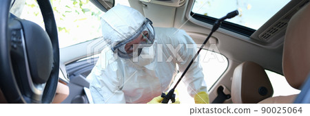 A man in protective clothing treats the interior of a car 90025064