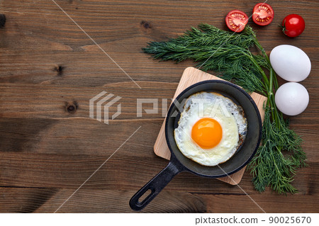 Fried chicken egg in a small frying pan with a stand, a bunch of dill, tomatoes 90025670