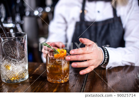Charming girl barkeeper formulates a cocktail 90025714