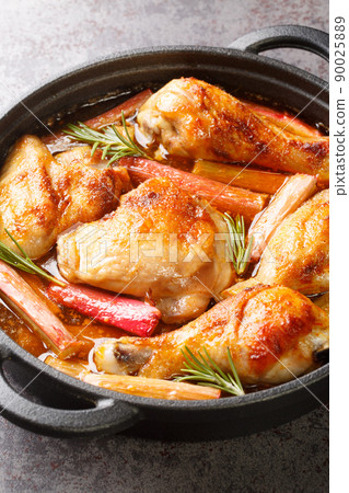 Baked chicken with rhubarb and white wine close-up in a frying pan. vertical 90025889