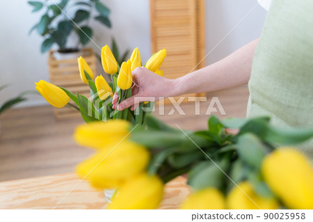The florist places yellow tulips in a vase. Work in a flower shop. Blooming bright flowers The florist places yellow tulips in a vase. Work in a flower shop. Blooming bright flowers 90025958