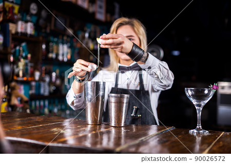 Sweet woman barkeeper makes a show creating a cocktail in pub 90026572