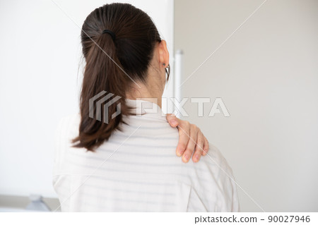 A woman suffering from stiff shoulders at work 90027946