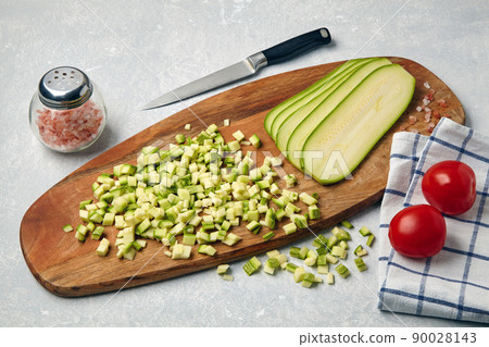 Sliced zucchini courgette vegetables on a wooden cutting board Sliced zucchini courgette vegetables on a wooden cutting board 90028143