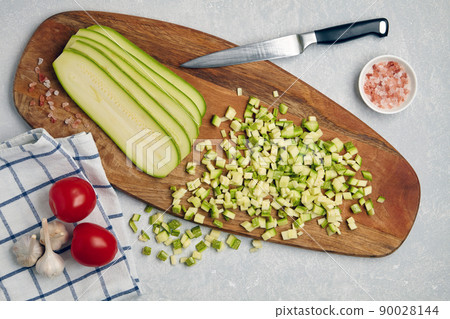 Sliced zucchini courgette vegetables on a wooden cutting board, tomatoes Sliced zucchini courgette vegetables on a wooden cutting board, tomatoes 90028144