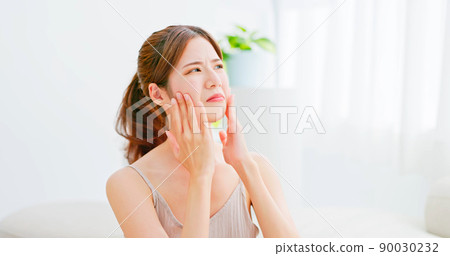 woman unhappy touch her face 90030232