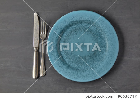 Blue plate on a dark concrete background with cutlery Blue plate on a dark concrete background with cutlery 90030787