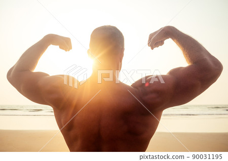 young brutal male bodybuilder shows athletic figure strong torso at sunset on beach .sexy boxers training exercise. 90031195