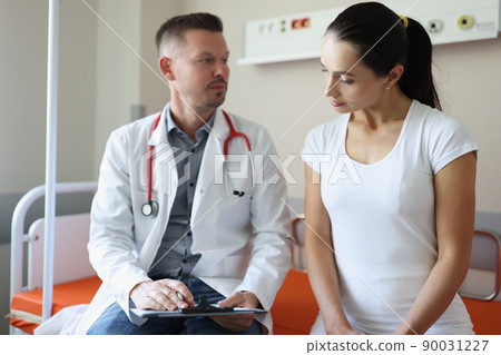 Male doctor communicates with female patient in clinic Male doctor communicates with female patient in clinic 90031227