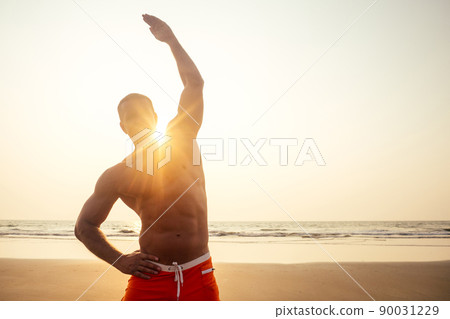 young brutal male bodybuilder shows athletic figure strong torso at sunset on beach .sexy boxers training exercise. 90031229