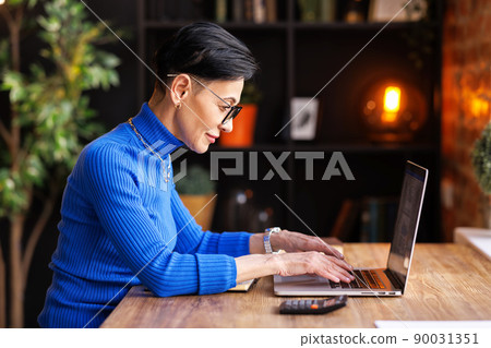 Mature businesswoman using laptop in home office Mature businesswoman using laptop in home office 90031351