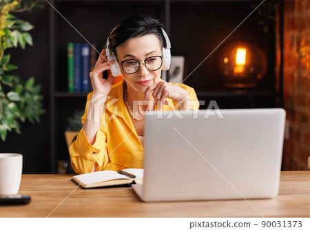 Middle aged woman making video call in home office Middle aged woman making video call in home office 90031373
