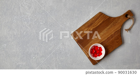 Brown wooden cutting board with red caramel hearts in a bowl 90031630