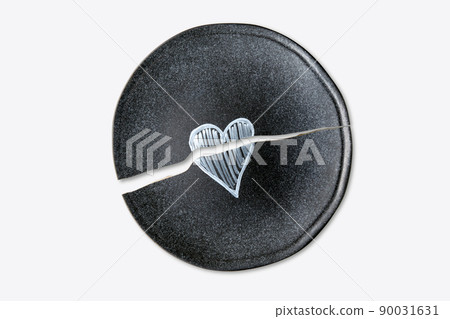 Broken ceramic plate with a painted heart isolated on a white background 90031631