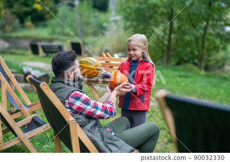 Dad and daughter sorting the pumpkings in the yard Dad and daughter sorting the pumpkings in the yard 90032330