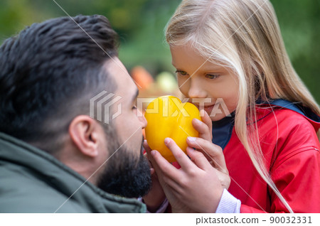 A dark-haired man and his daughter spending time on a farm A dark-haired man and his daughter spending time on a farm 90032331